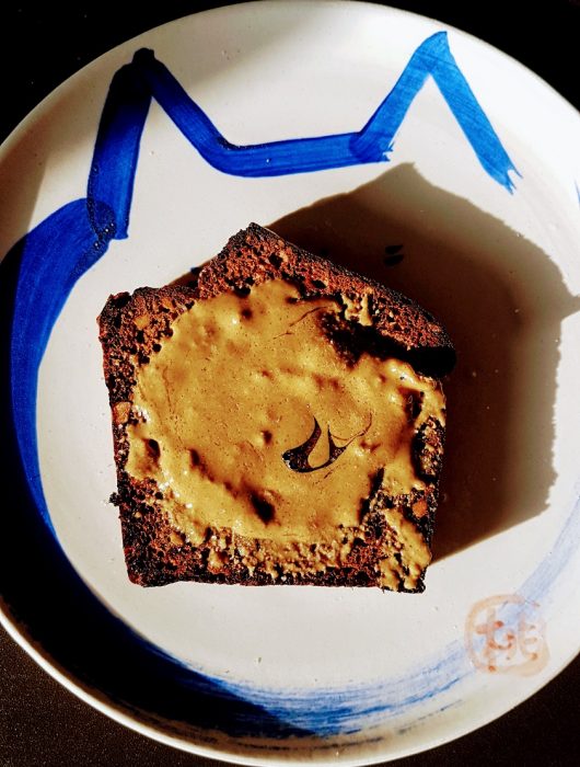 A slice of banana bread with tahini and honey spread on Japanese ceramic plate