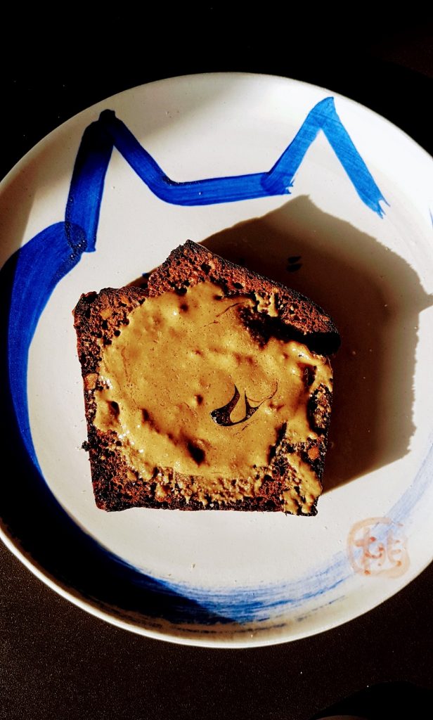 A slice of banana bread with tahini and honey spread on a Japanese style ceramic plate