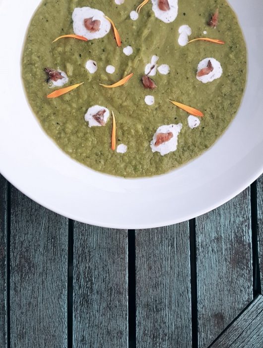 Creamy pea soup with avocado, zucchini, yogurt, anchovy, dandelion petals