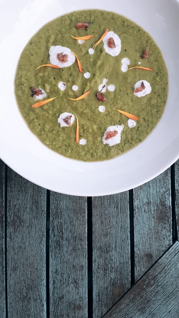 Creamy pea soup with avocado, zucchini, yogurt, anchovy, dandelion petals