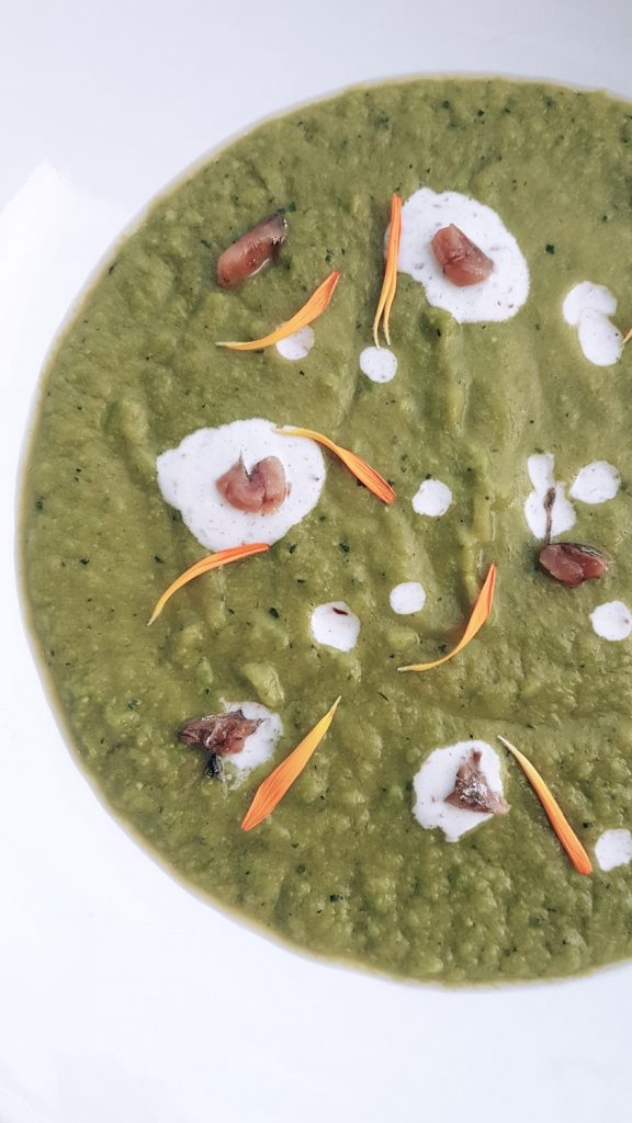 Creamy pea soup with avocado, zucchini, yogurt, anchovy, dandelion petals